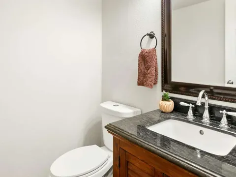 Lavabo com bancada em granito escuro e espelho emoldurado